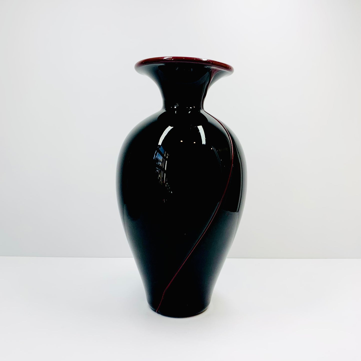 Vintage Taiwanese black glass vase with burgundy trimming across